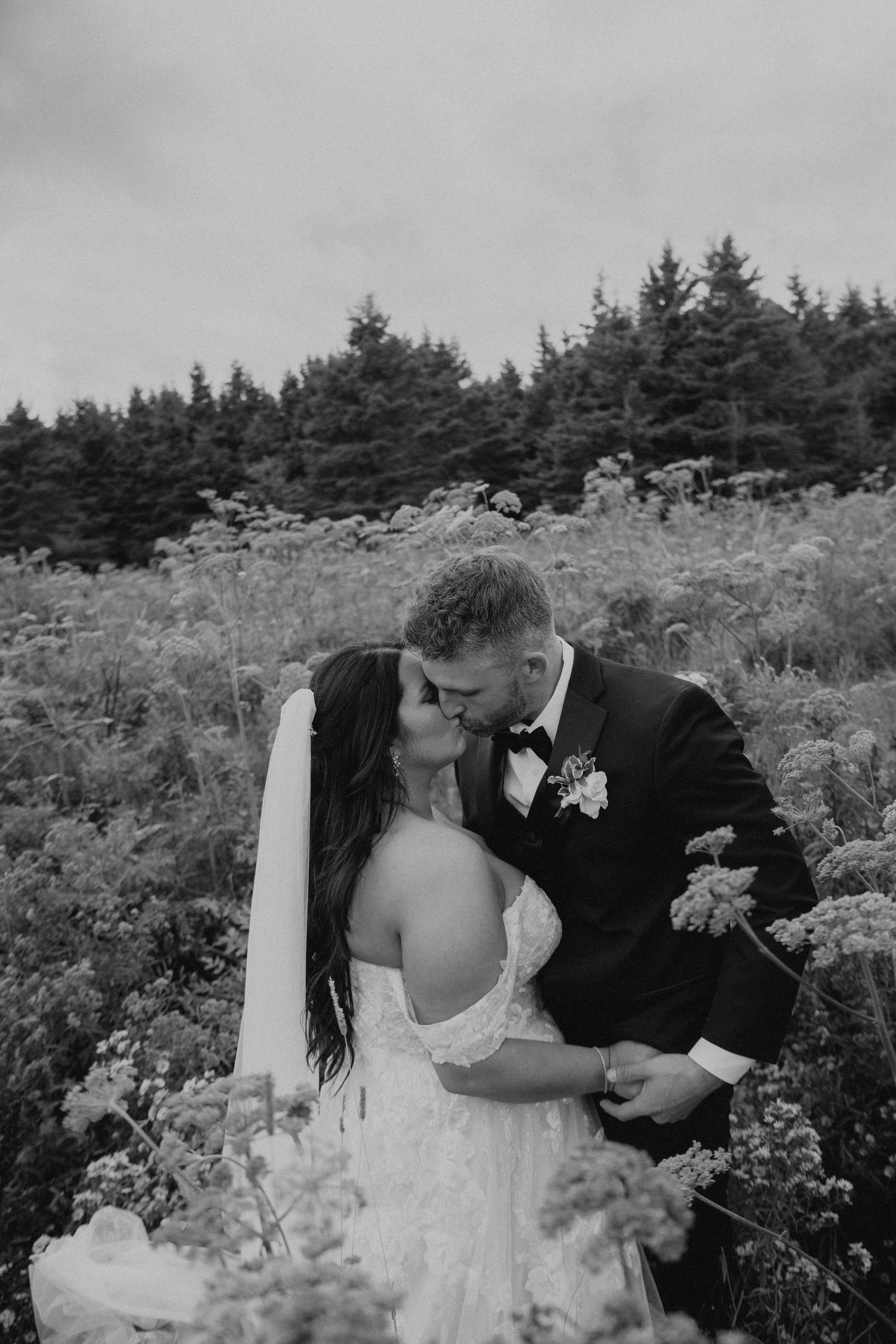 An intimate wedding moment captured in black and white among wild summer flowers.