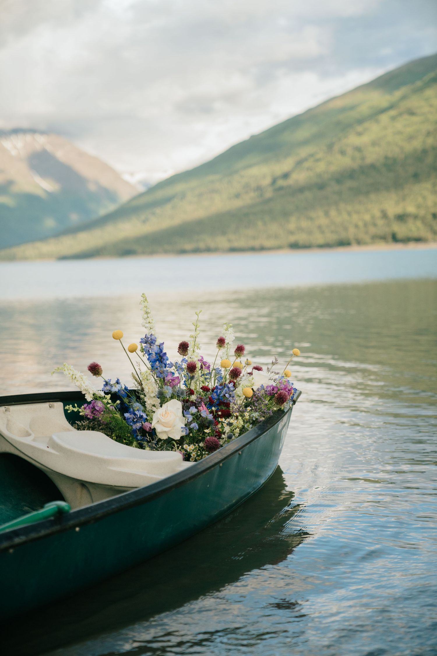 Canoes at Eklutna Lake, Alaska decorated with wildflower bouquets float on a serene mountain lake.