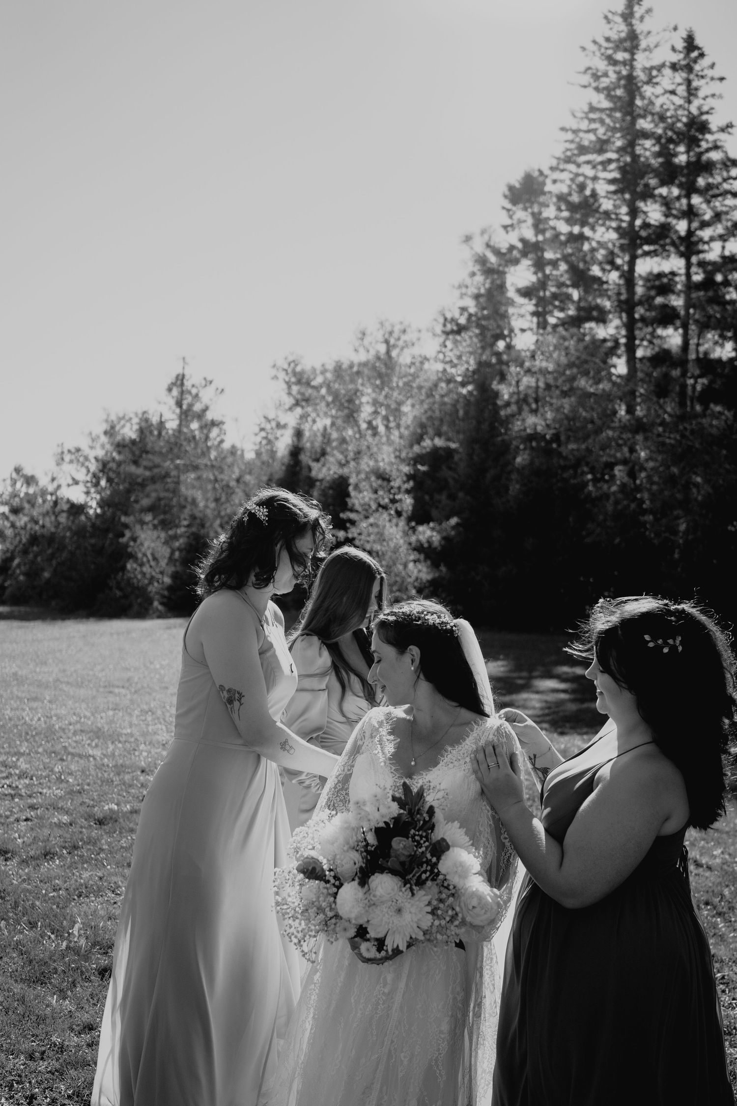 Black and white photograph of wedding party members standing together in an outdoor setting.