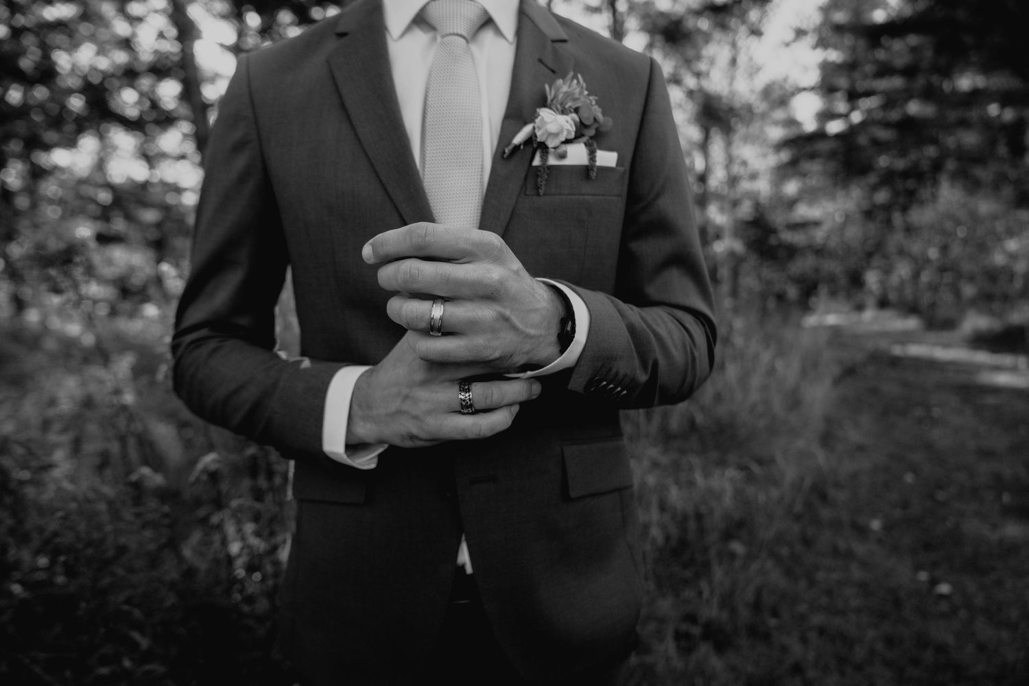 Black and white series showing formal suit details and hands holding phone.