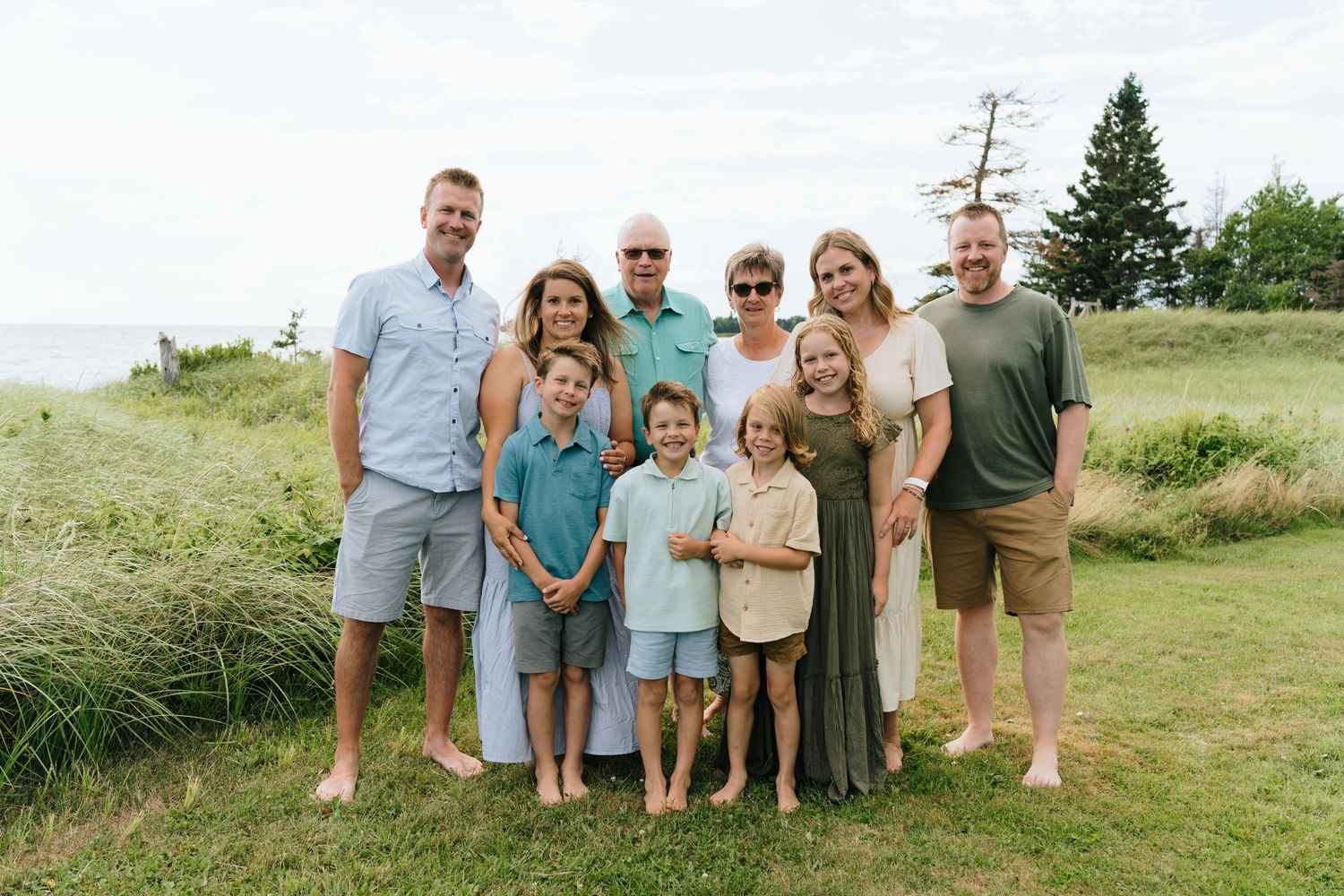 Group photo of family members standing together in casual summer attire on grassy hill.