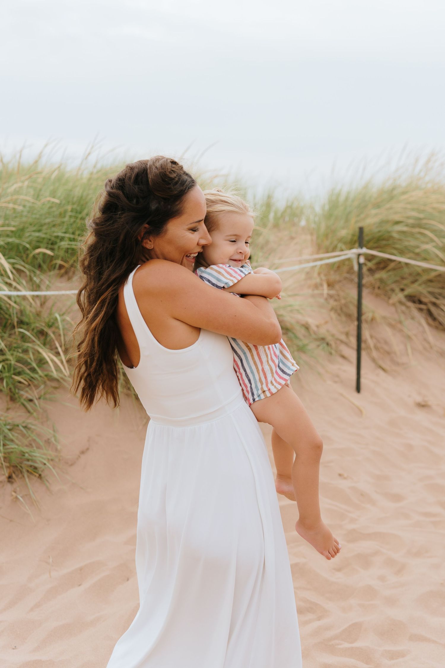 Tender beach moments captured between parent and child in white summer clothing.