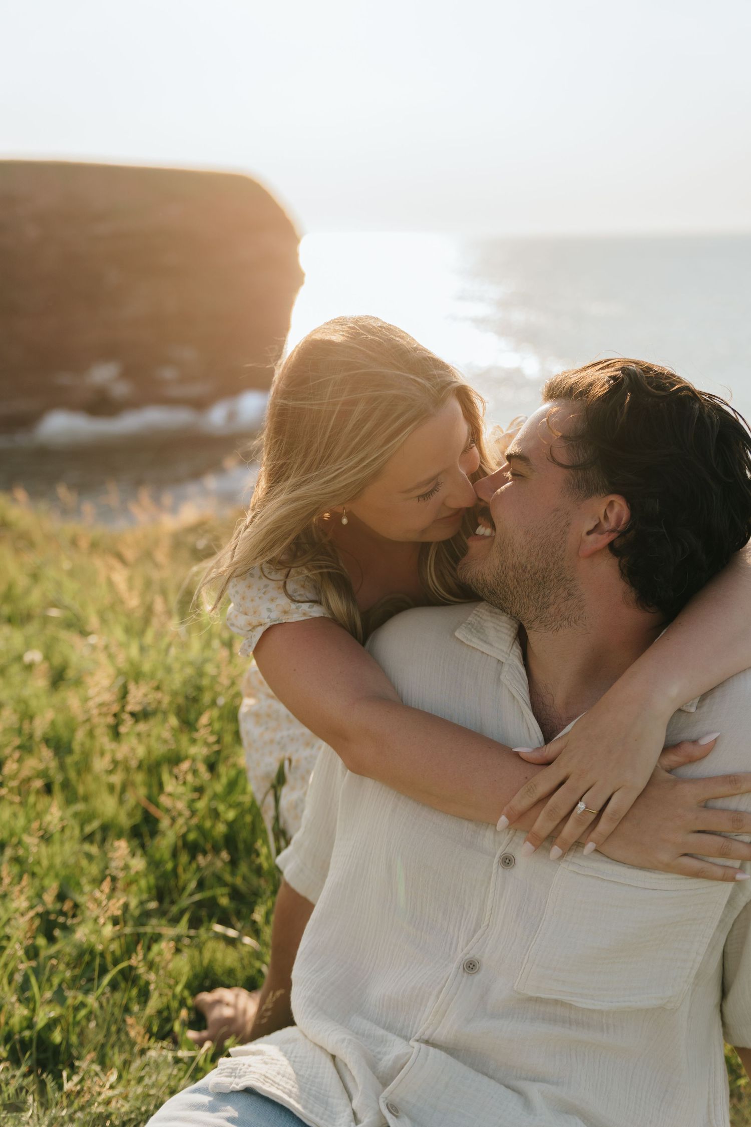 Intimate moment shared between couple on grass during golden hour photoshoot.