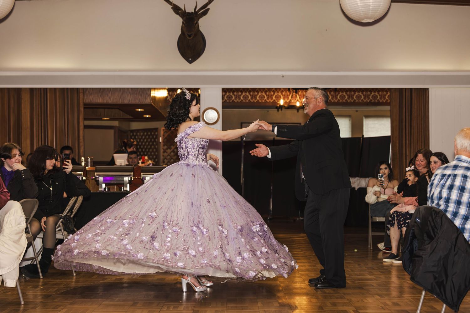 A dancer in a flowing lavender ballgown twirls gracefully on a dance floor during a formal event.