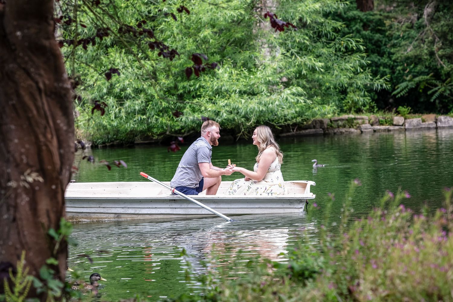 Two small white boats float peacefully on a tranquil lake surrounded by lush green foliage and trees.