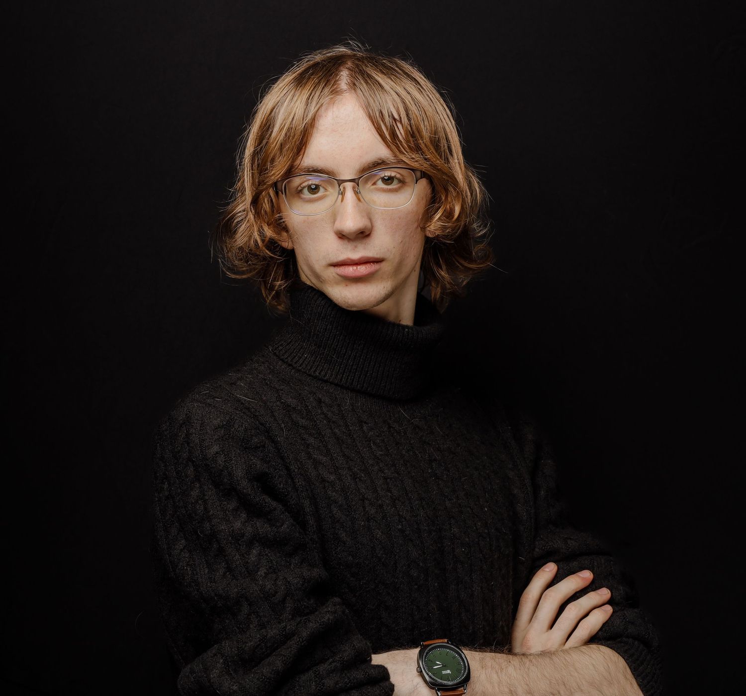 Portrait of a person in black turtleneck sweater against dark background.