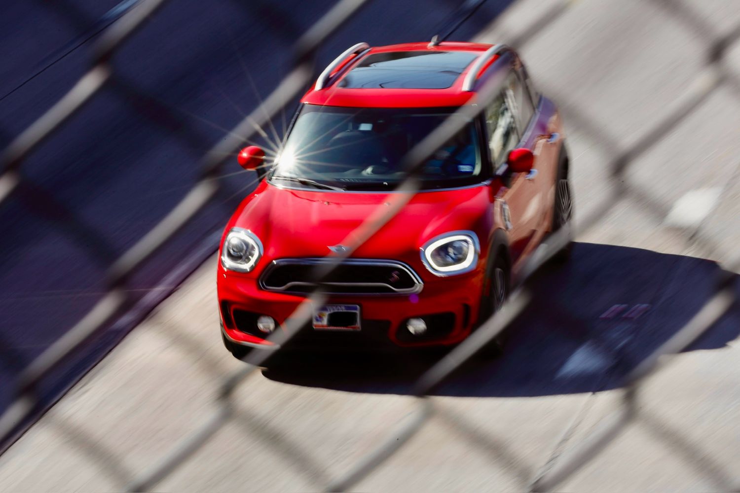 Motion-blurred red MINI Cooper racing on a track with dramatic lighting.