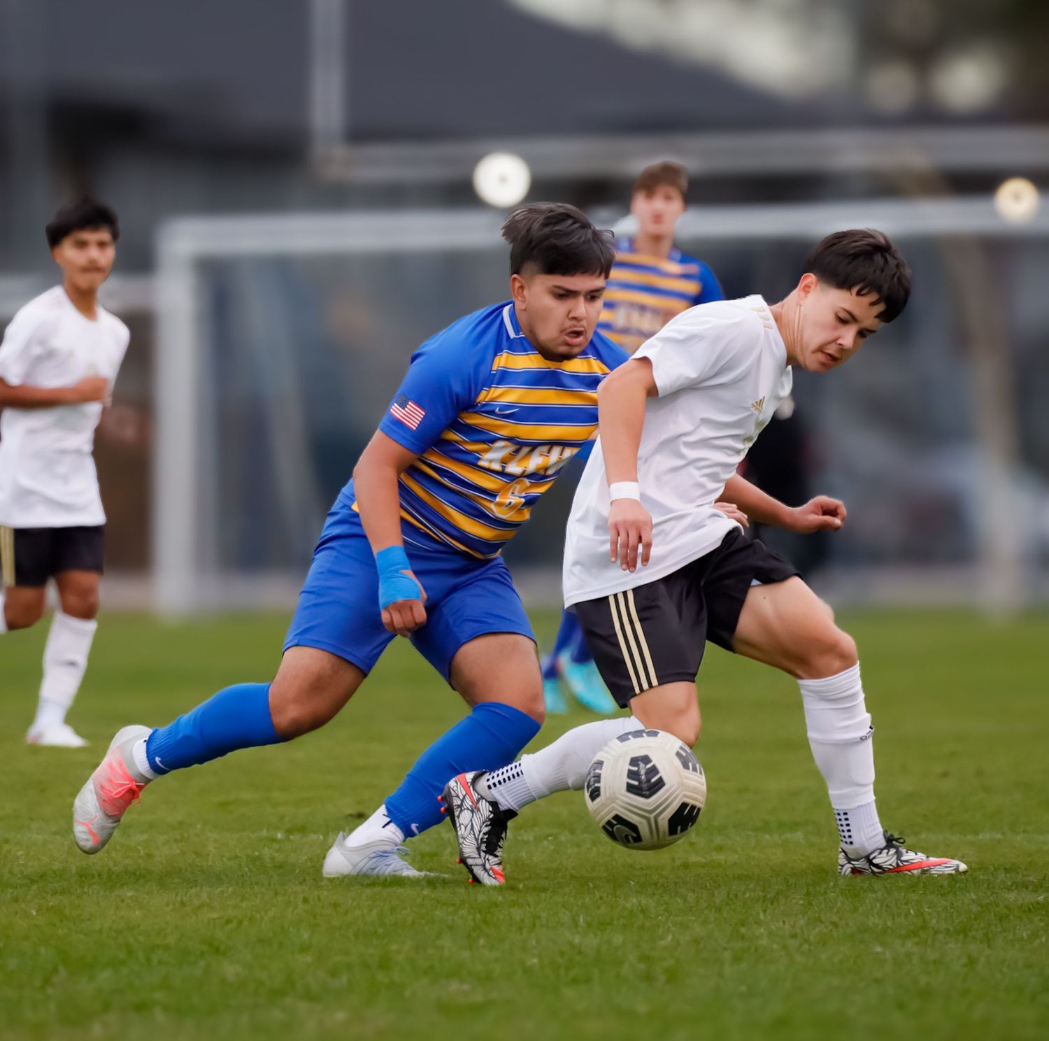 Soccer players from opposing teams battle for possession of the ball during an intense match on the field.