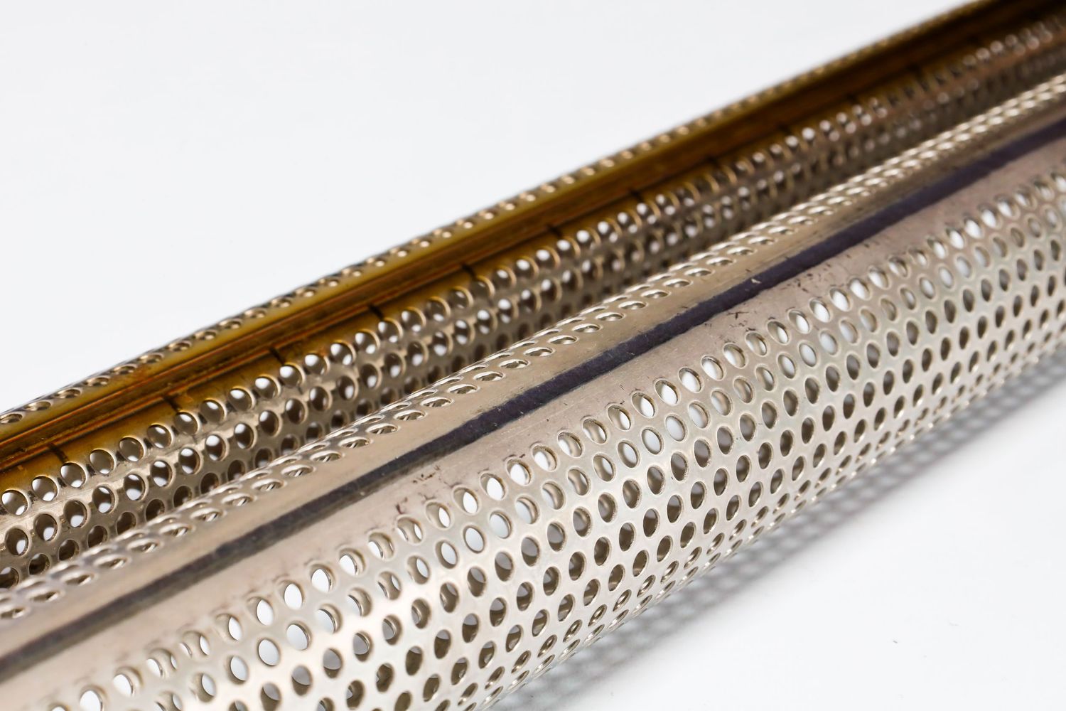 Close-up view of perforated metal tubing showing precise circular holes in a shiny metallic surface.