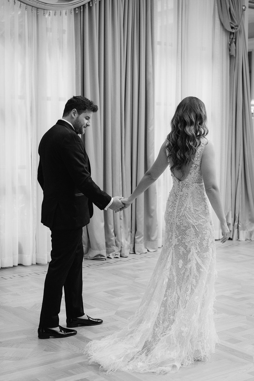 bride and groom walking in a hotel living room holding hands
