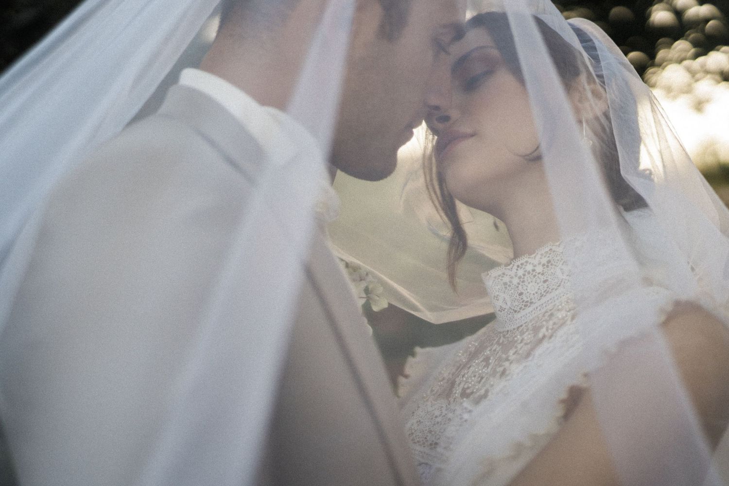 Bride and groom kissing under the veil