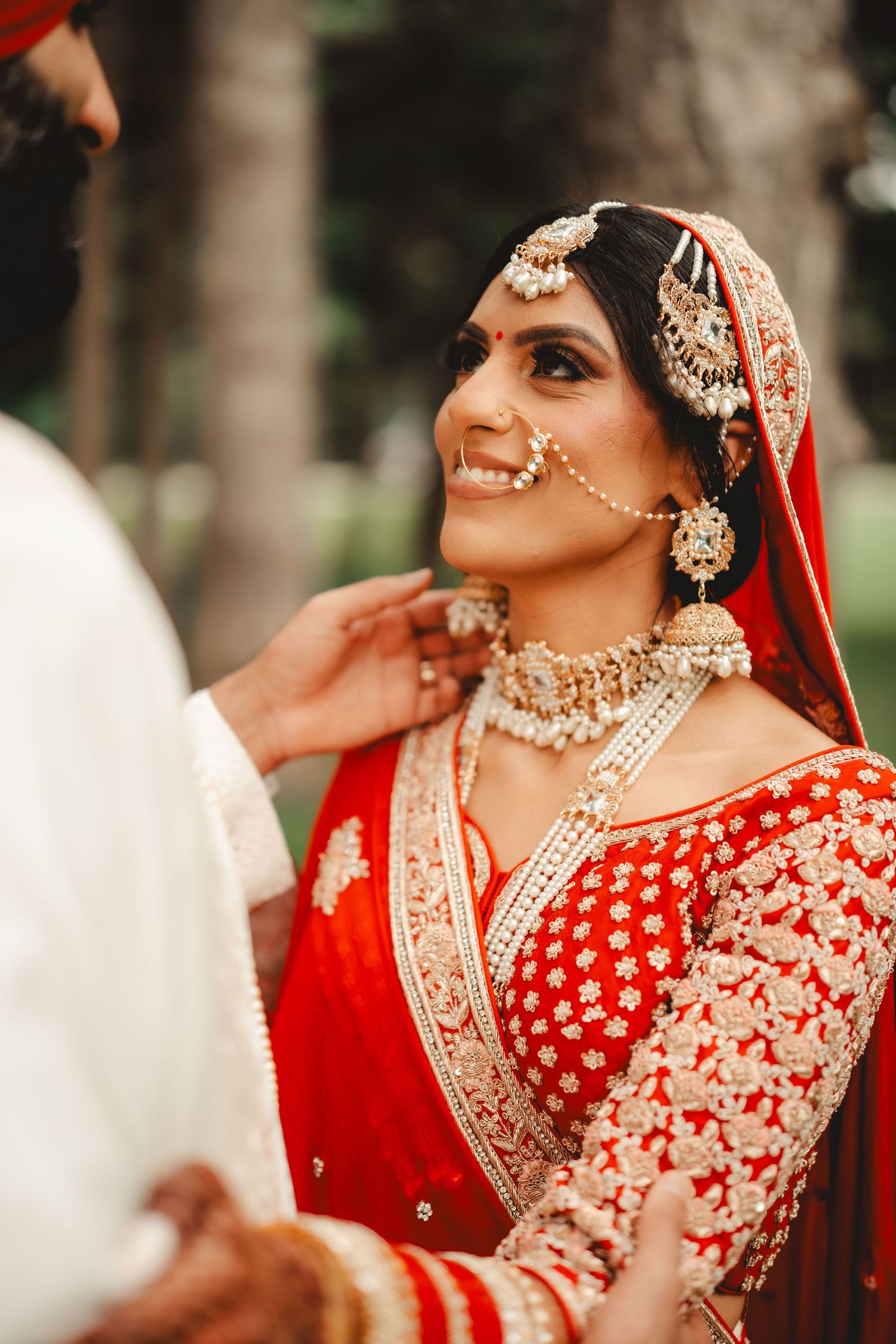 Close-up of traditional Indian bridal jewelry and red embroidered wedding attire.