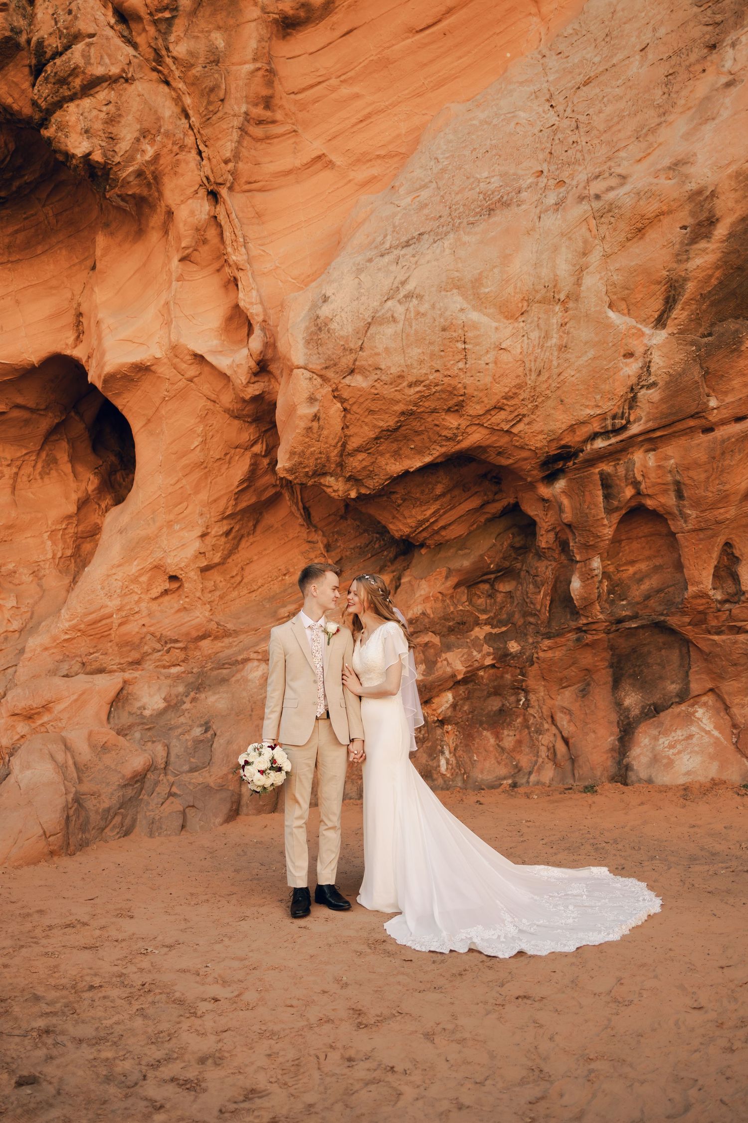 Wedding portraits against dramatic red rock formations in desert landscape.