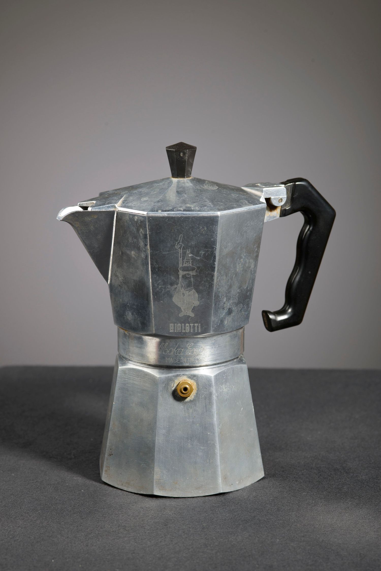 Multiple views of a vintage aluminum Bialetti Moka Express stovetop coffee maker against a dark background.