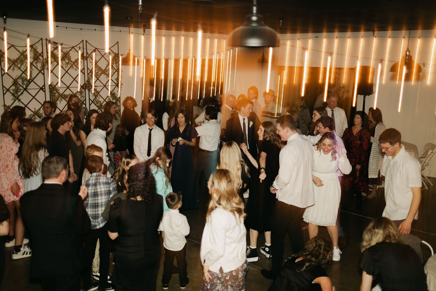 Wedding reception with warm lighting and crowd of guests dancing.