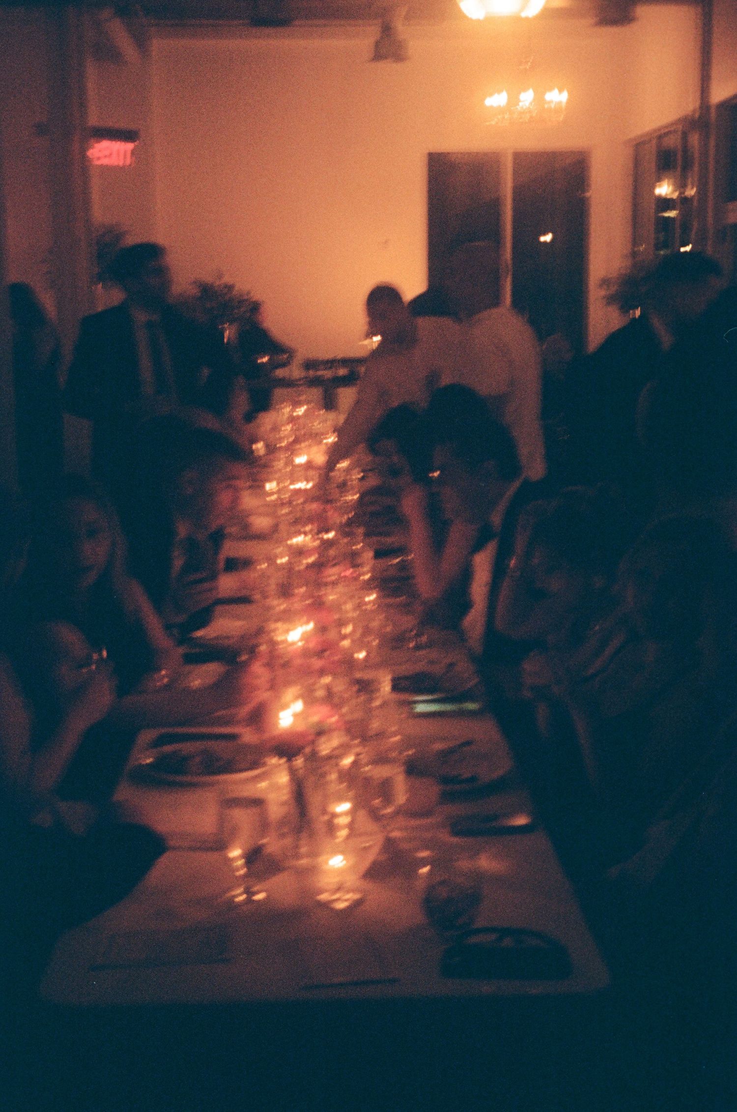Silhouettes of people gathered around a dimly lit dining table with candlelight creating a warm, intimate atmosphere.