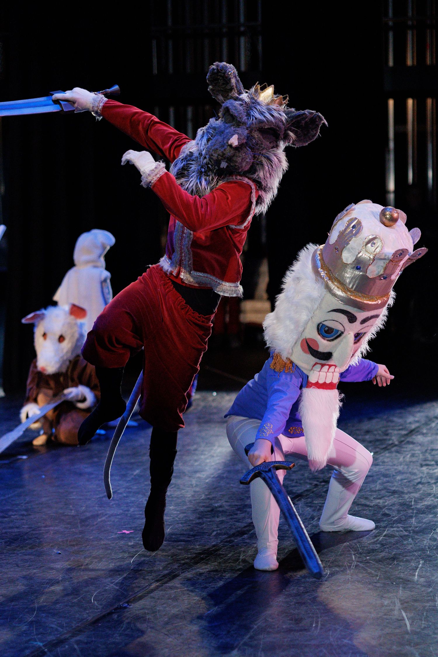 Dynamic performance sequence shows figure in red costume dancing with white mascot character on dark stage.