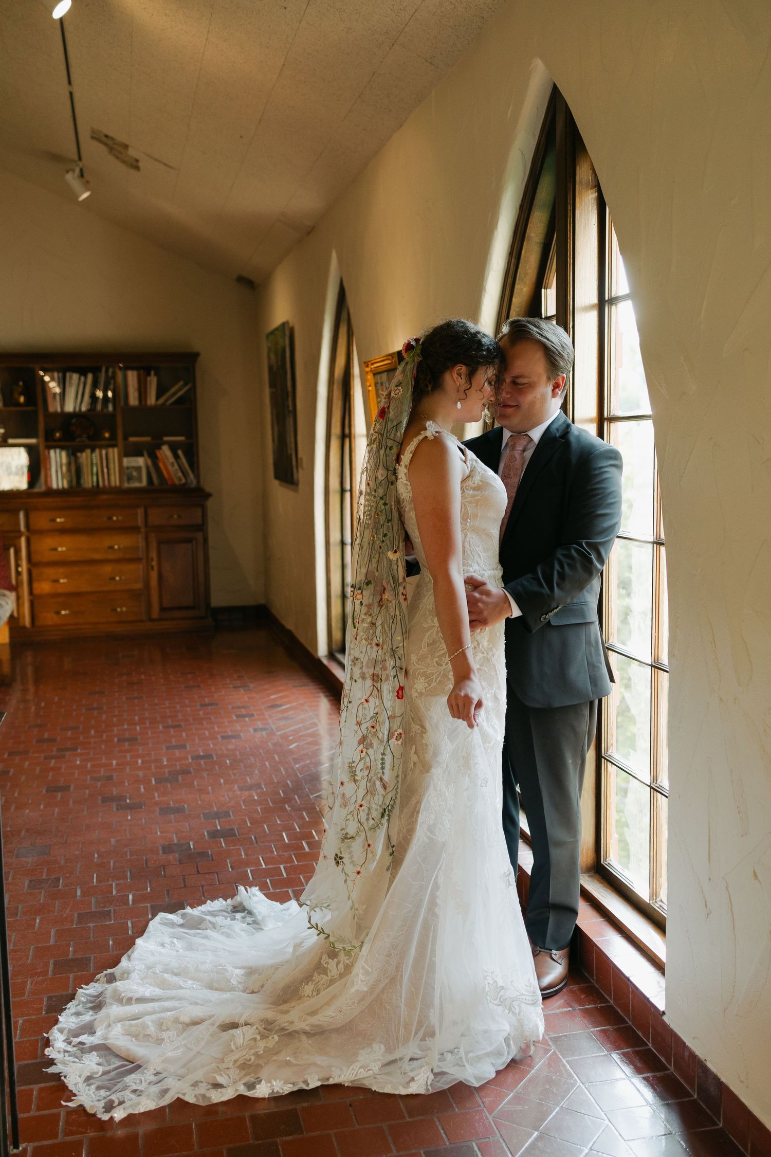 Romantic wedding portrait in an arched hallway with brick floors and natural lighting.
