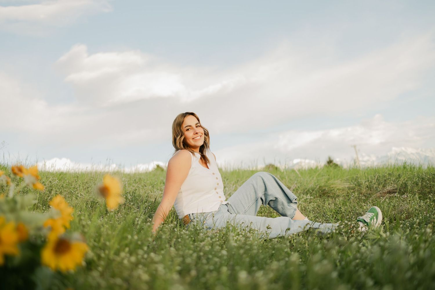 A person lies peacefully in a meadow of wildflowers under blue skies.