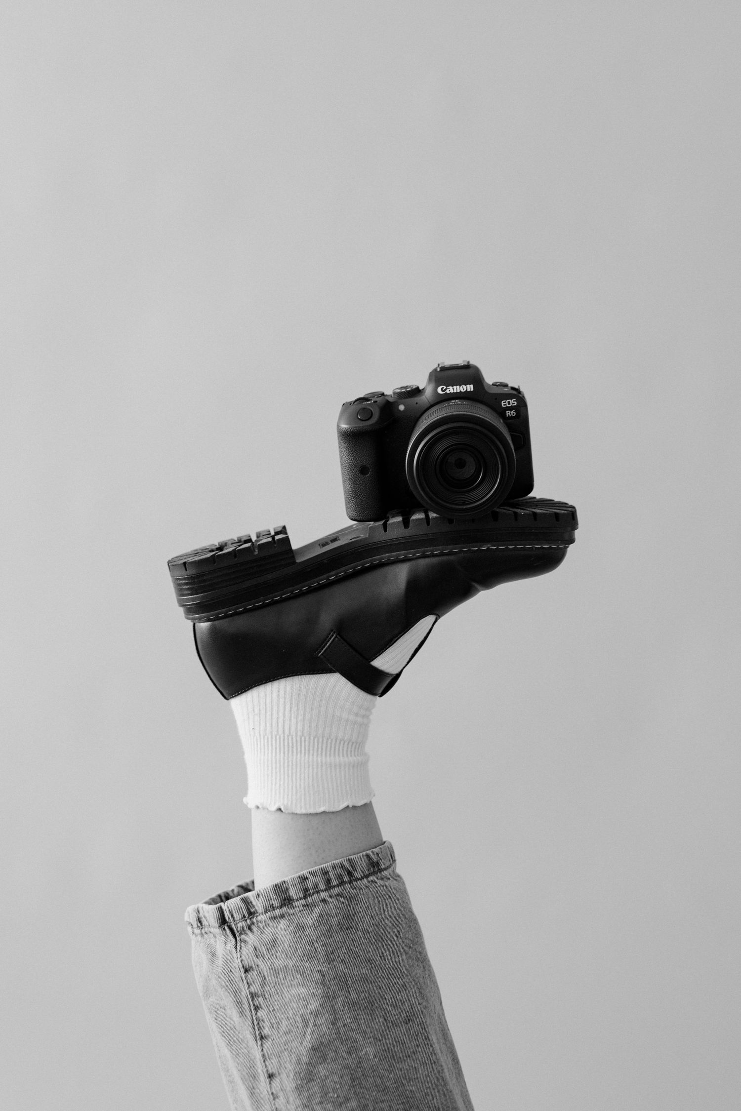 Black dress shoes with white socks against grey background in minimalist style.
