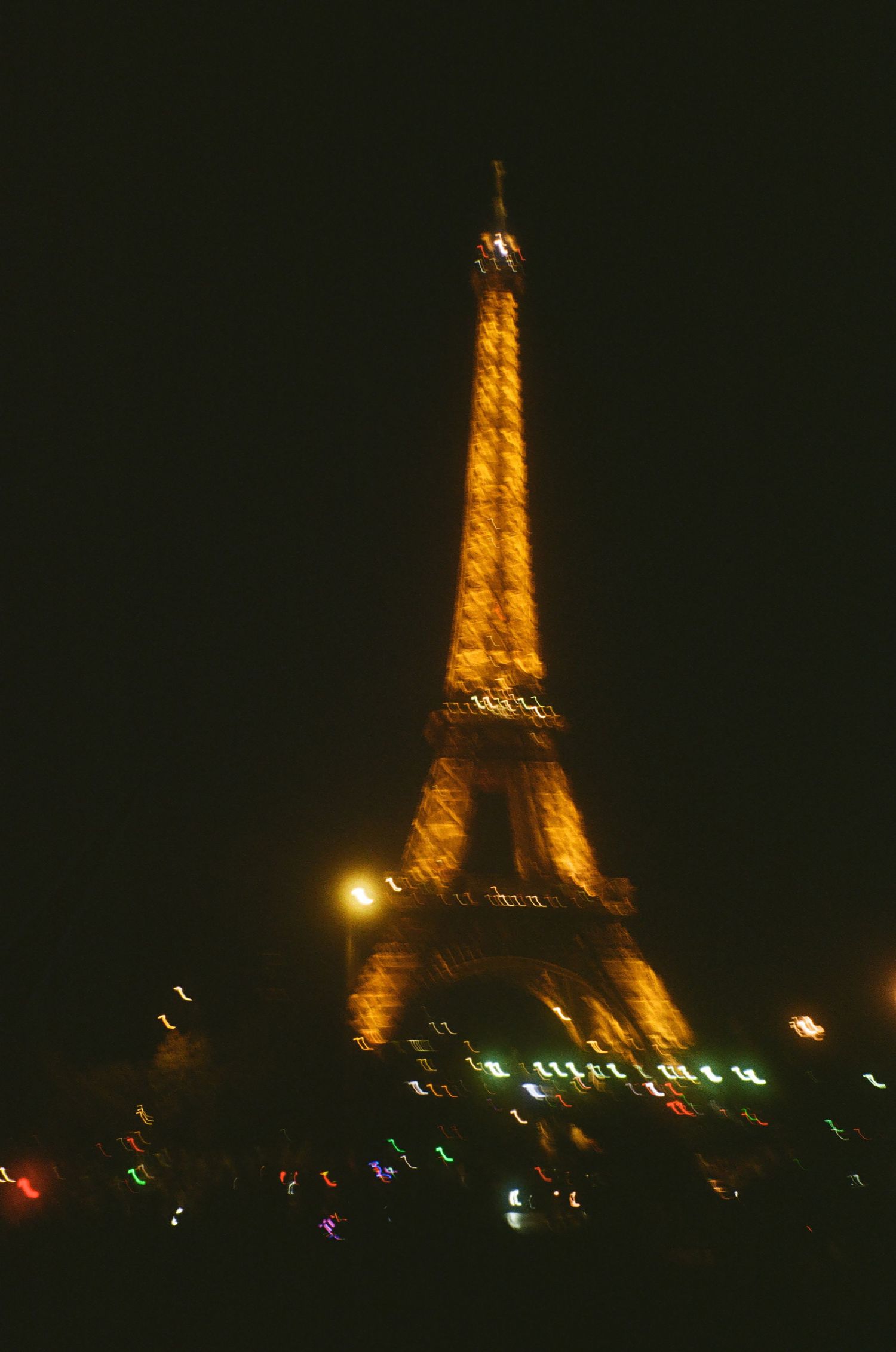 The Eiffel Tower illuminated in golden light against a dark night sky in Paris, France.