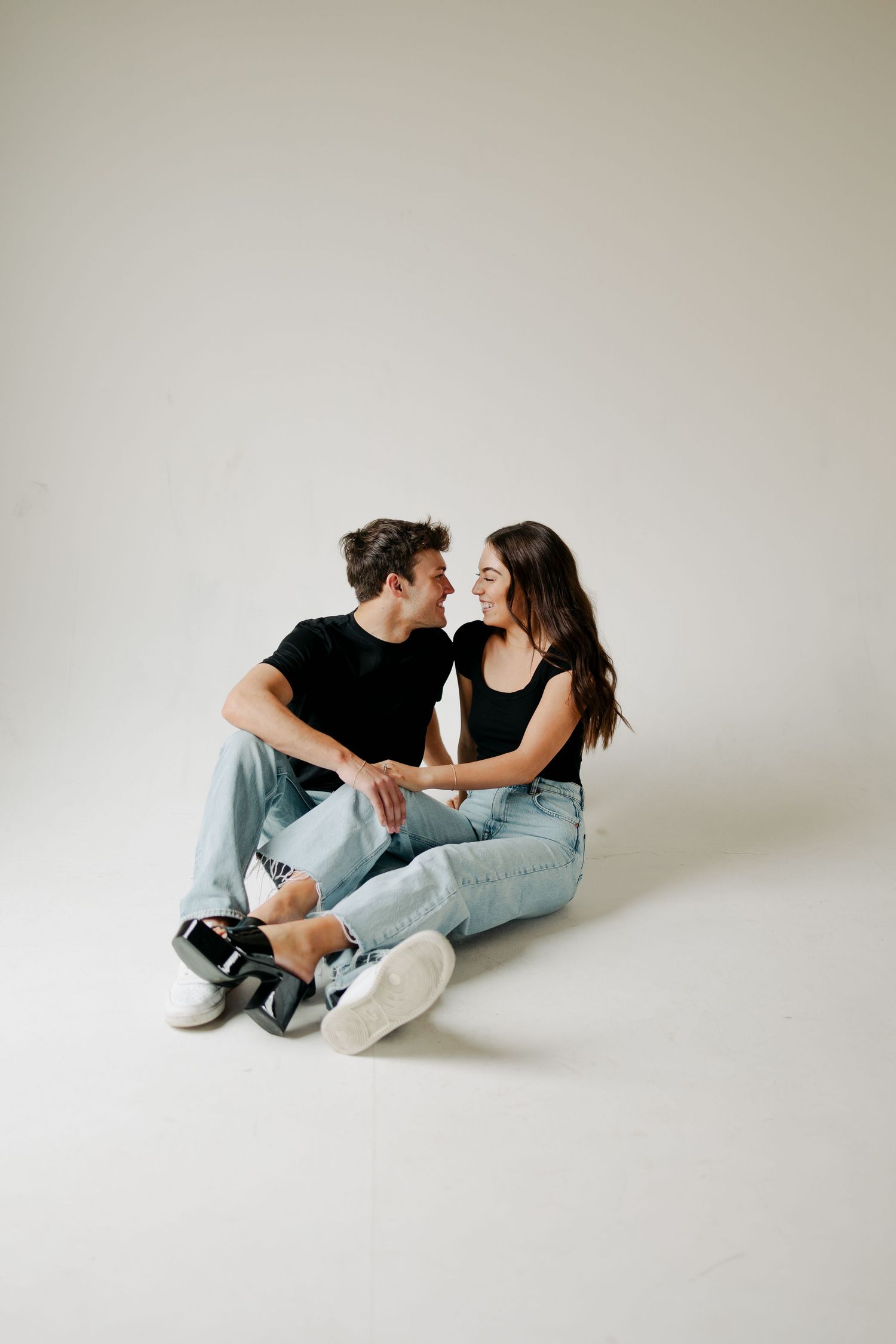 Minimalist studio portrait of couple in casual denim sitting close together.