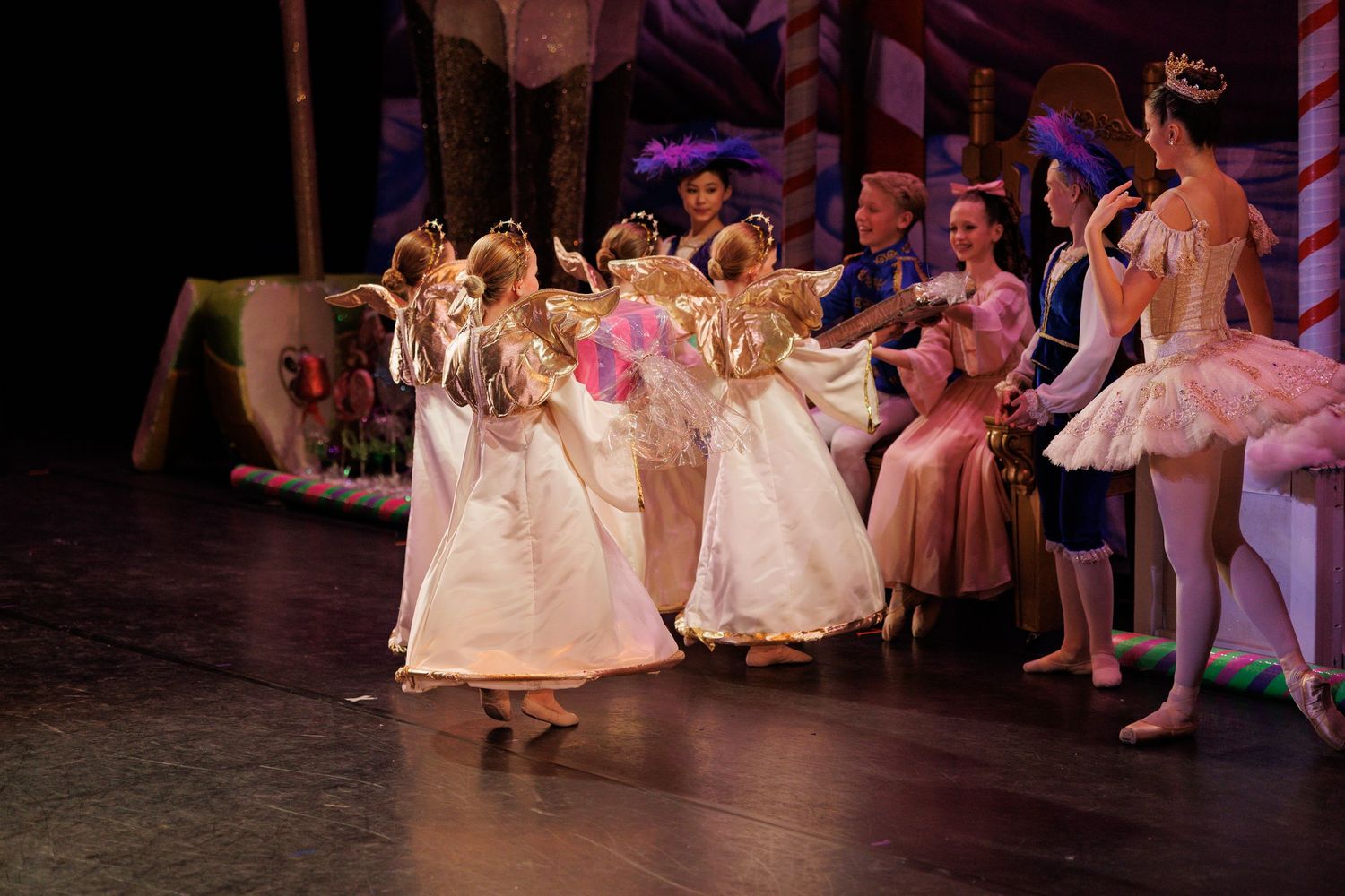 Ballet dancers in pink tutus perform gracefully on stage during a classical dance recital.
