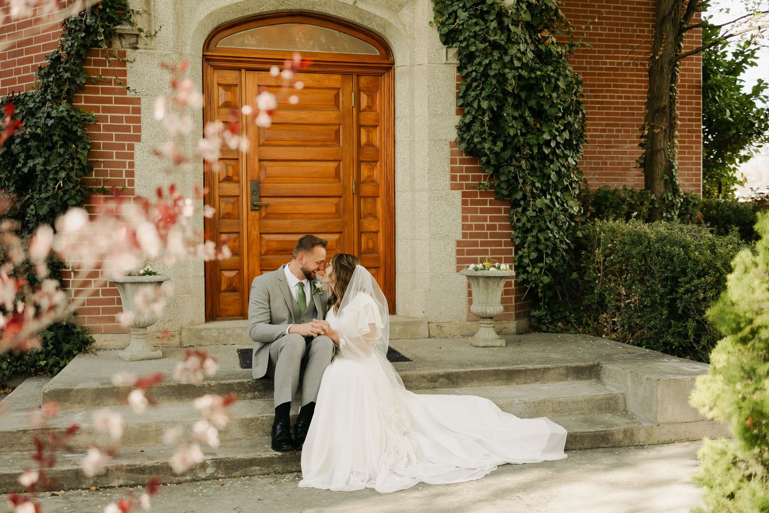 A romantic wedding moment on brick church steps with vintage wooden doors and climbing ivy.