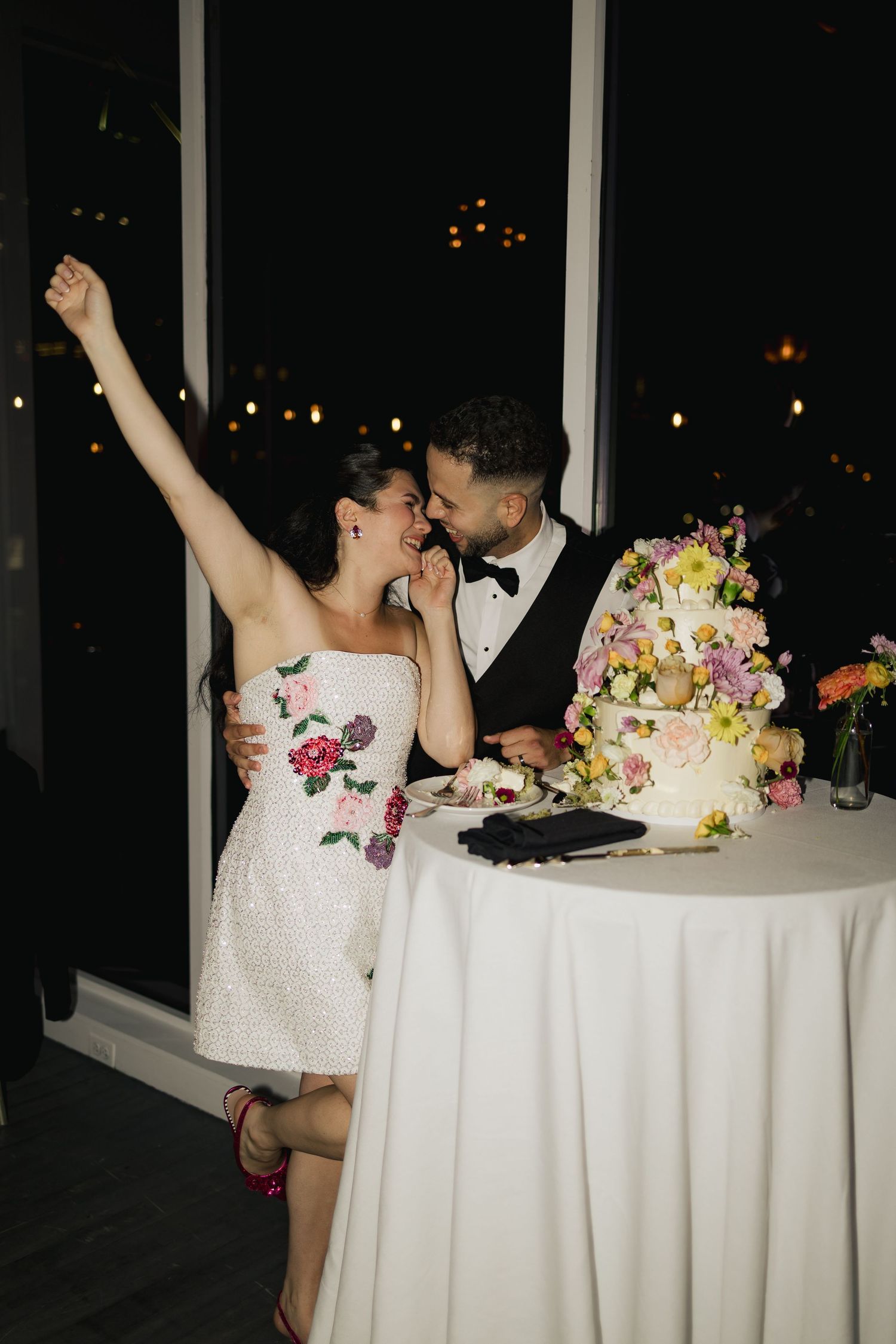 Newlyweds celebrate at their reception table with floral centerpieces and candlelight creating a romantic atmosphere.