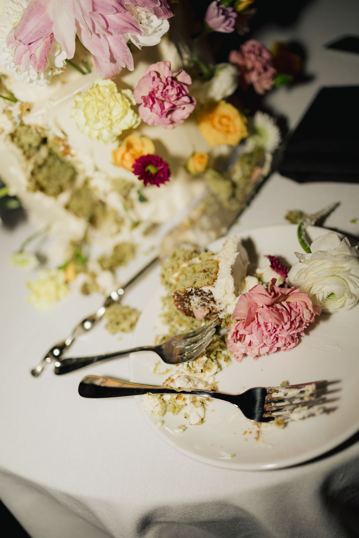 Close-up of scattered cake crumbs and flowers on a white plate after a wedding reception.
