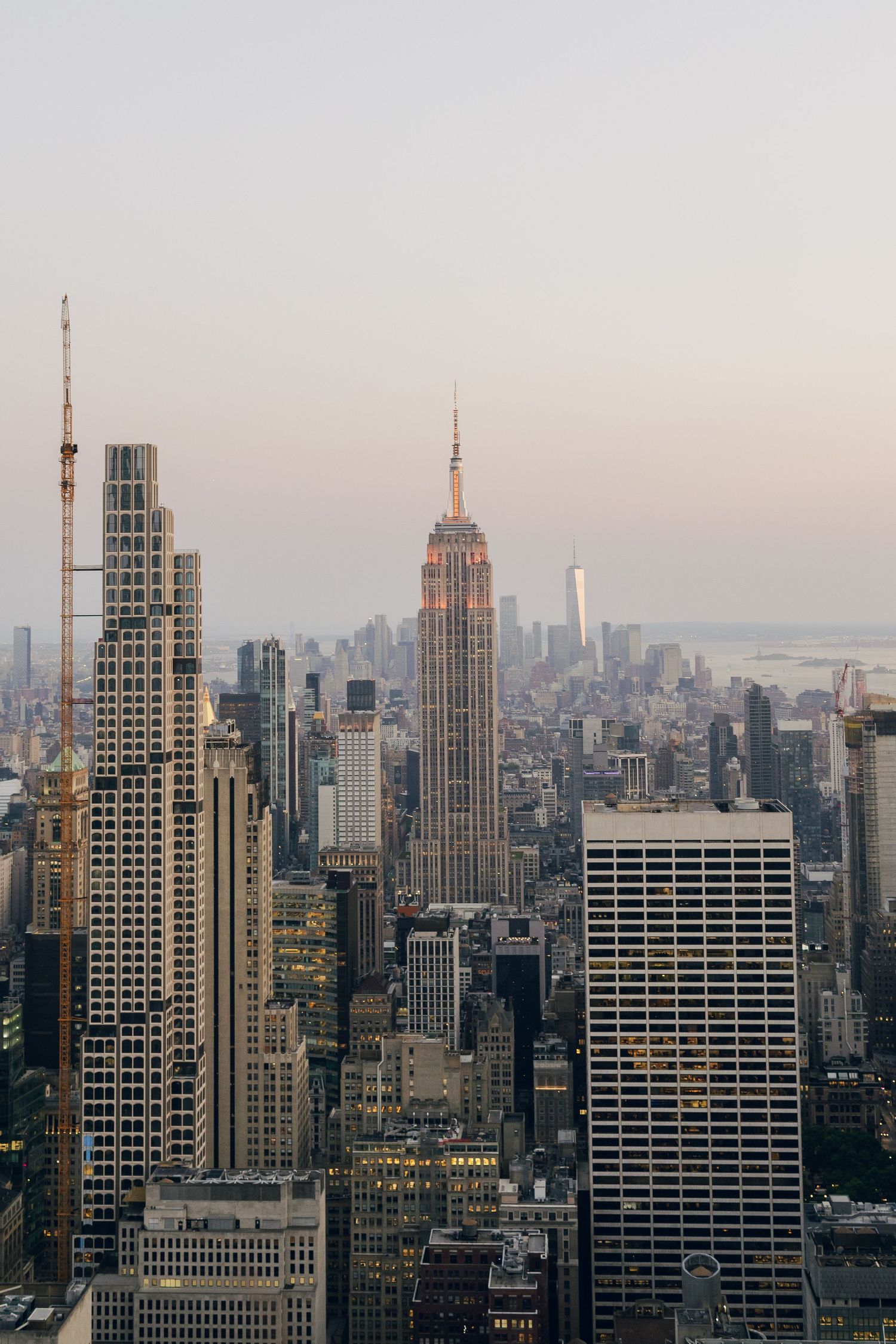 Aerial view of New York City skyline at dusk featuring the Empire State Building surrounded by skyscrapers.