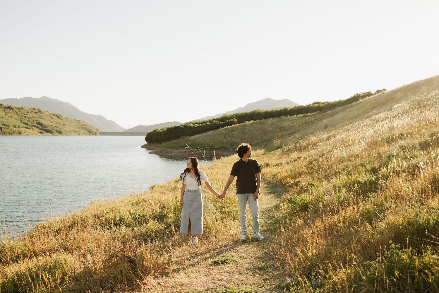 Distant view of couple walking along coastal hiking trail during golden hour.