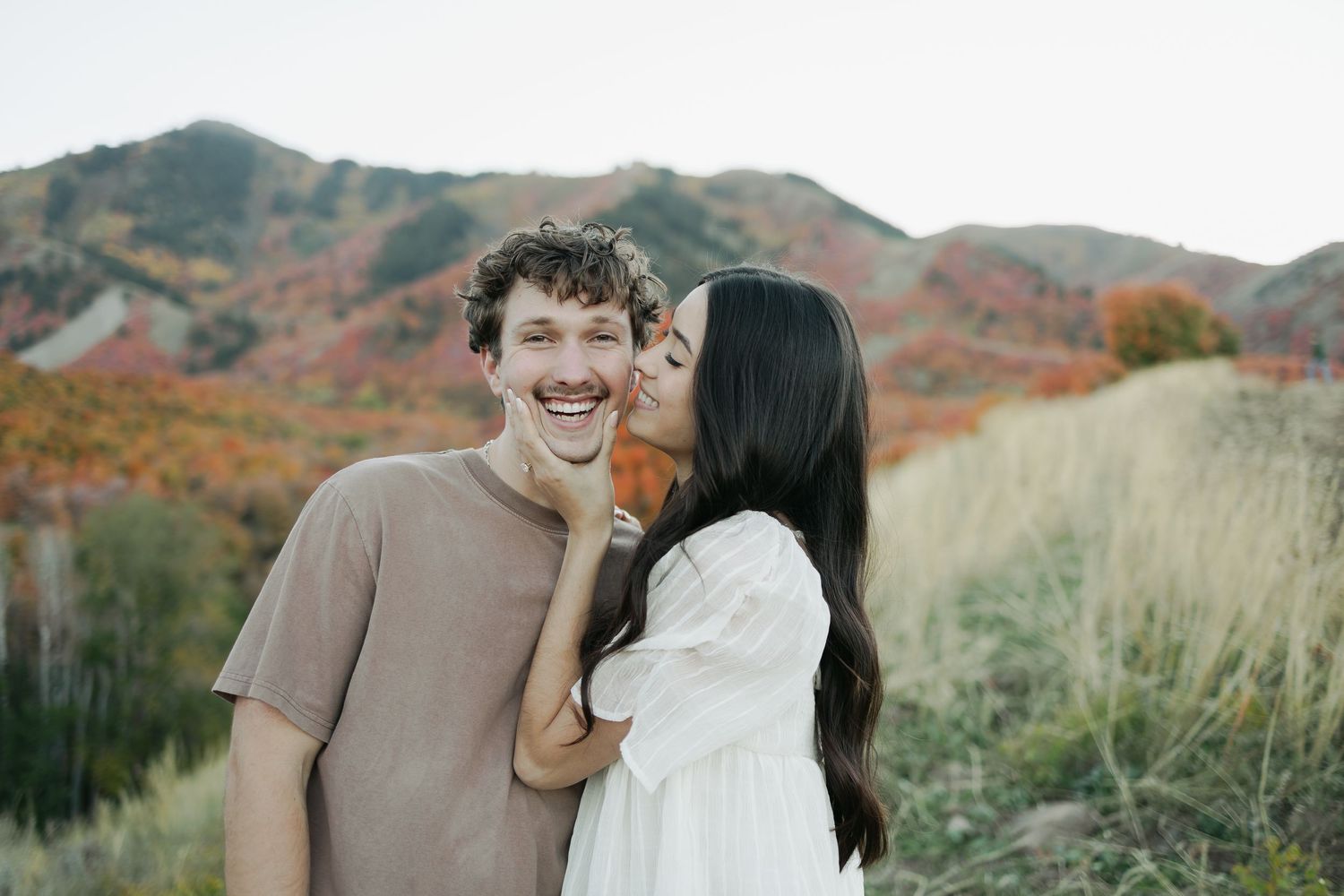A couple shares tender moments in front of scenic mountain landscapes.