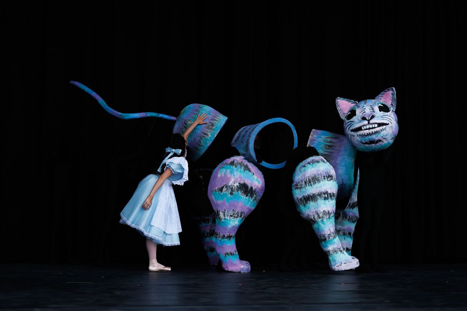 Whimsical decorative figures inspired by Alice in Wonderland featuring Cheshire cat and characters against black background.