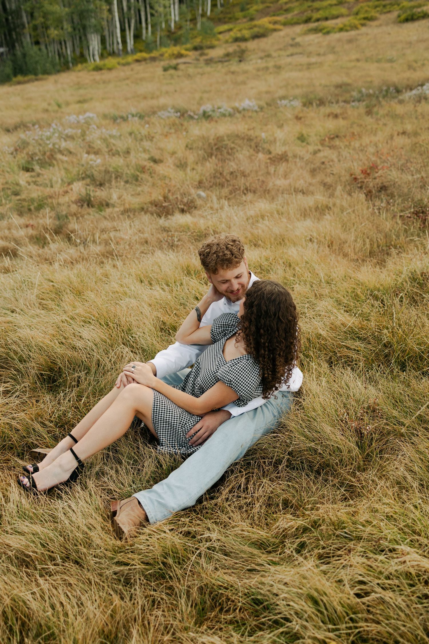 Couple embracing in tall mountain grass during autumn season.