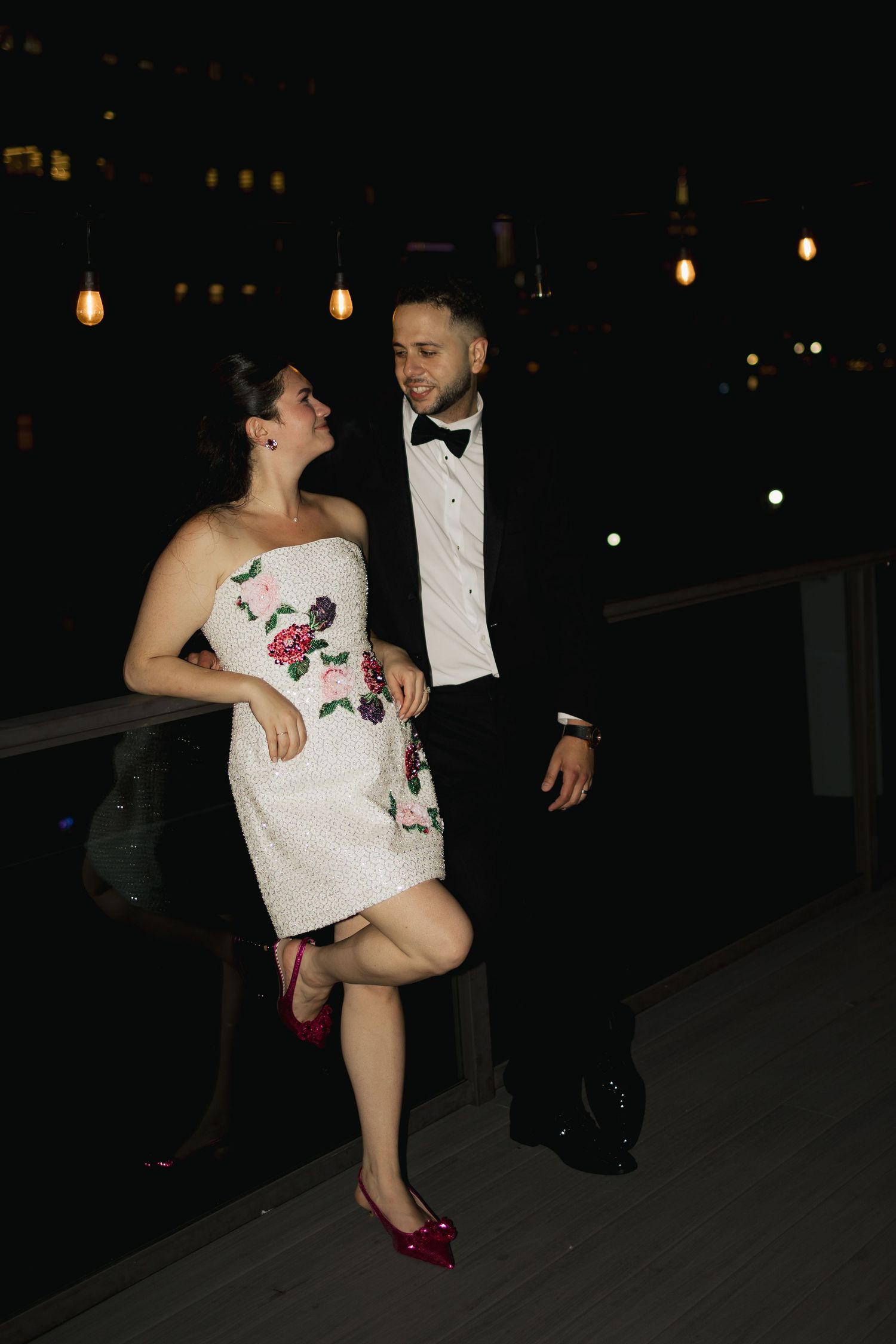 A couple shares a playful dance moment on an outdoor patio at night.