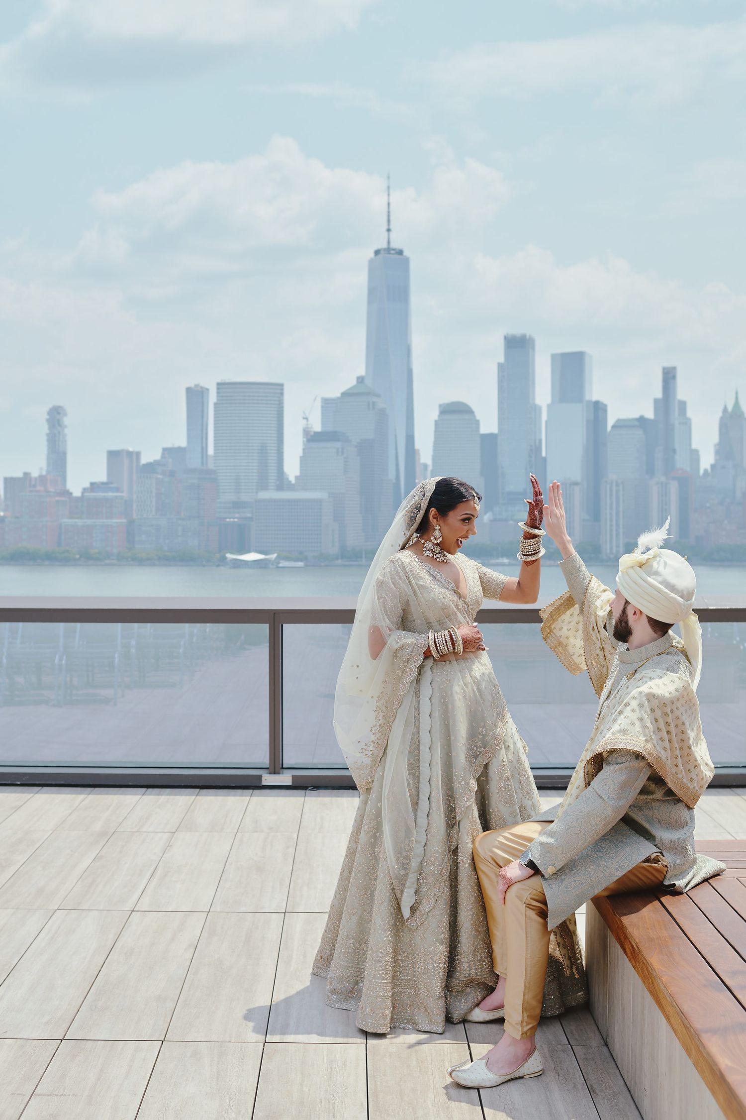 Couple in traditional Indian wedding attire sharing romantic moment against NYC skyline.