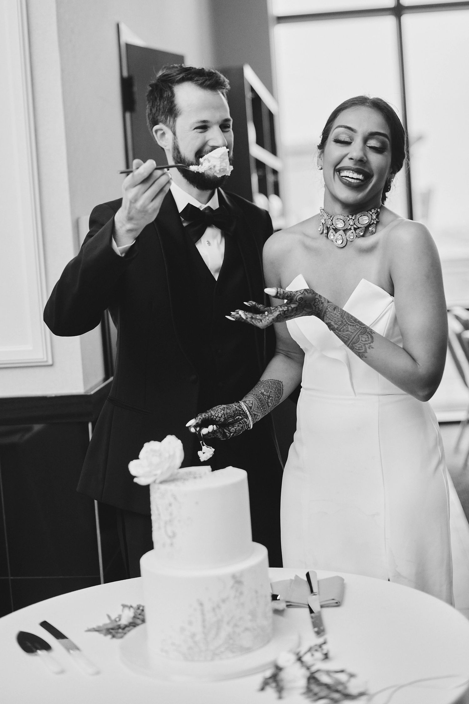 A joyful moment of a couple enjoying cake together at their wedding reception.