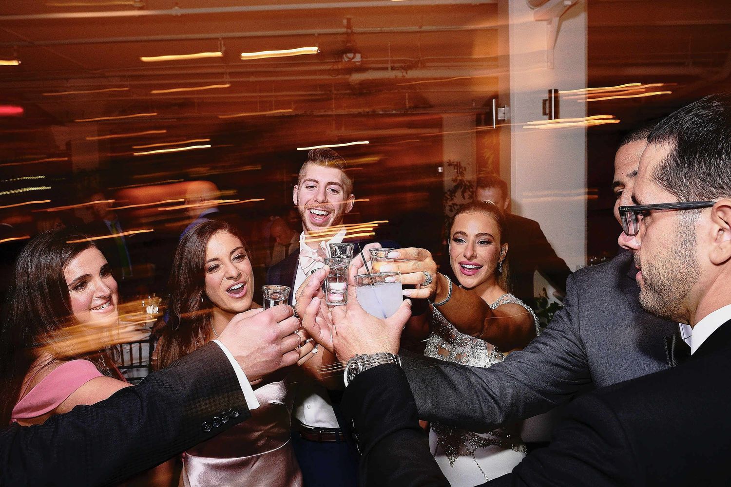 A celebratory group gathers to toast and clink glasses together at an indoor event.
