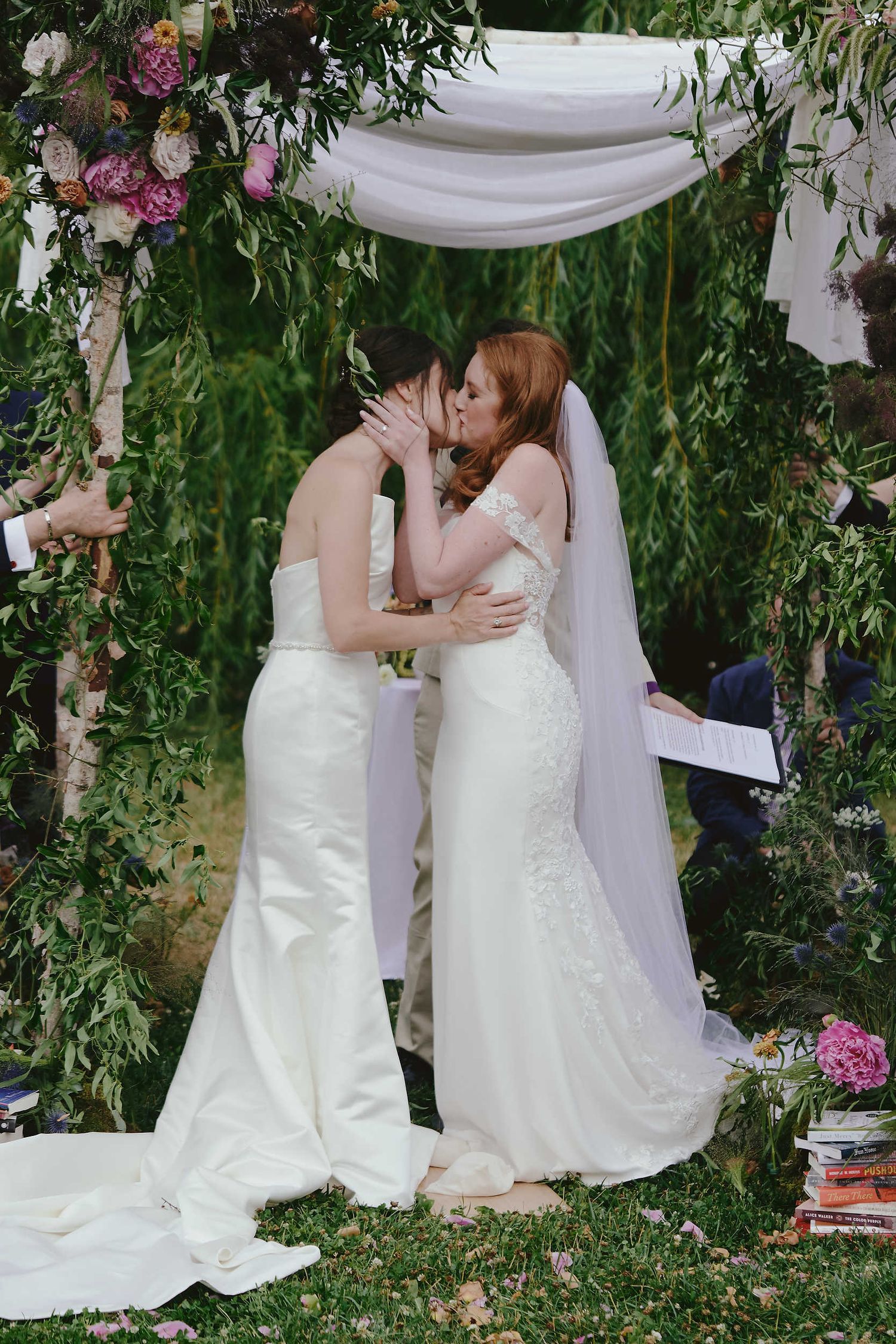 Romantic outdoor wedding ceremony under draped white fabric and floral arch with pink roses.