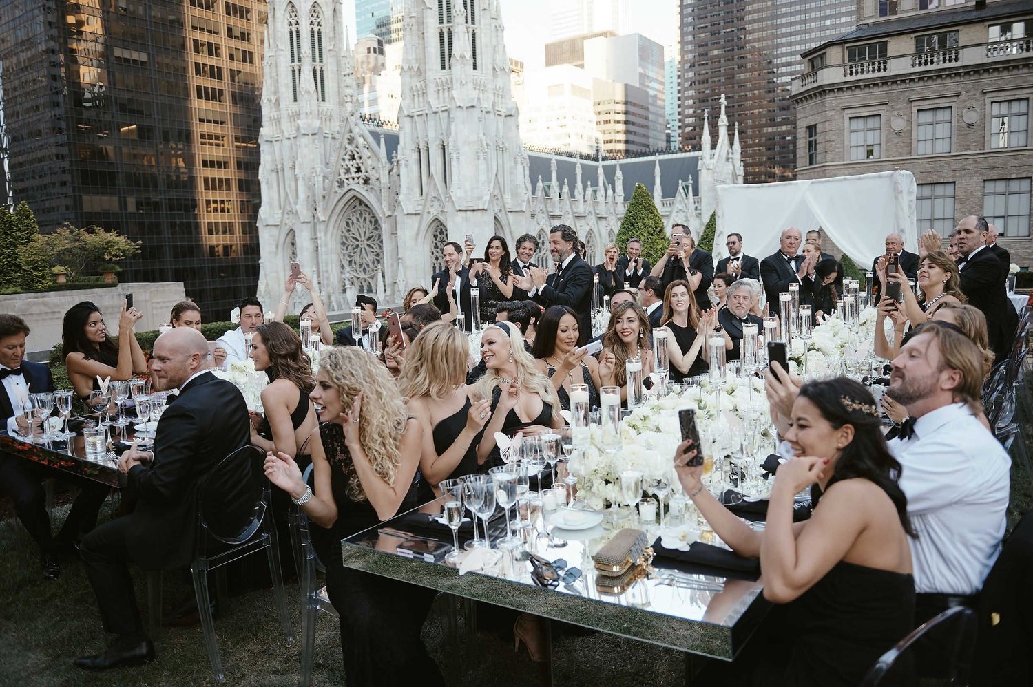 Guests enjoy dinner and drinks at an elegant rooftop event with St. Patrick's Cathedral visible in the New York City skyline.