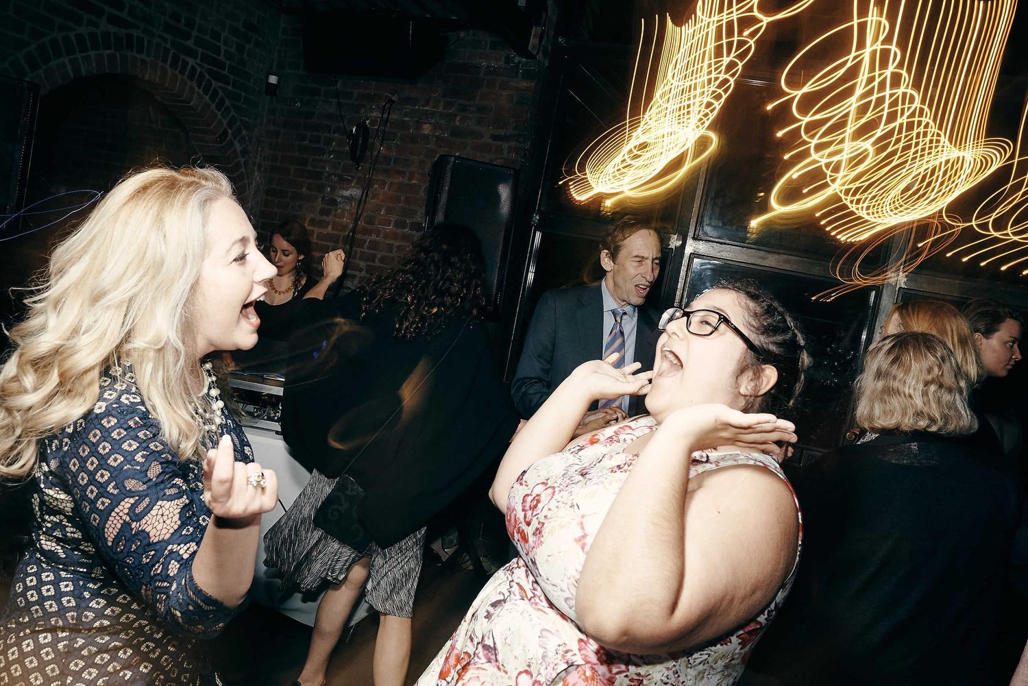 Two people sharing an energetic moment while dancing at a dimly lit party with neon lights.
