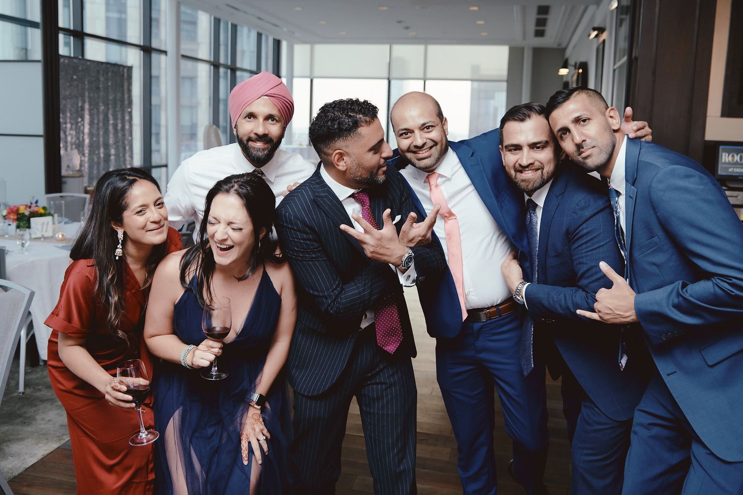 A group of formally dressed friends laughing and having fun at what appears to be an upscale indoor venue.