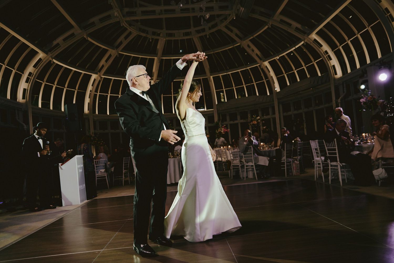 A couple shares their first dance as newlyweds under a round domed ceiling at an elegant indoor wedding reception.
