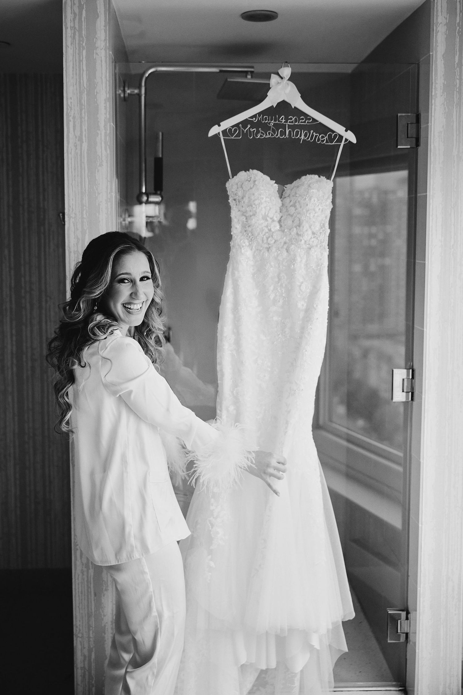 A lace wedding gown displayed on a hanger in a hotel hallway.
