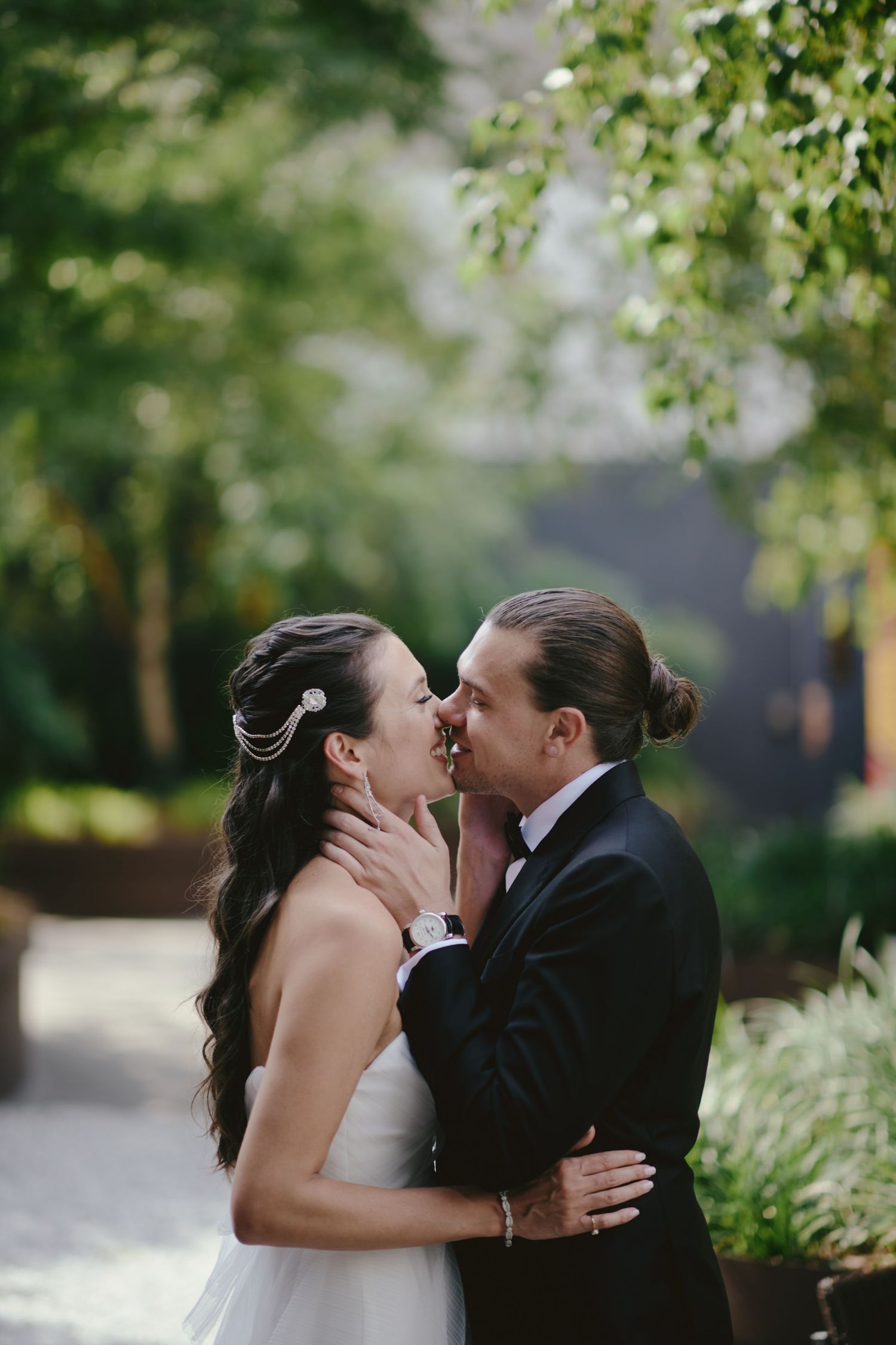A romantic moment between newlyweds sharing a tender kiss in a lush garden setting with soft natural lighting.