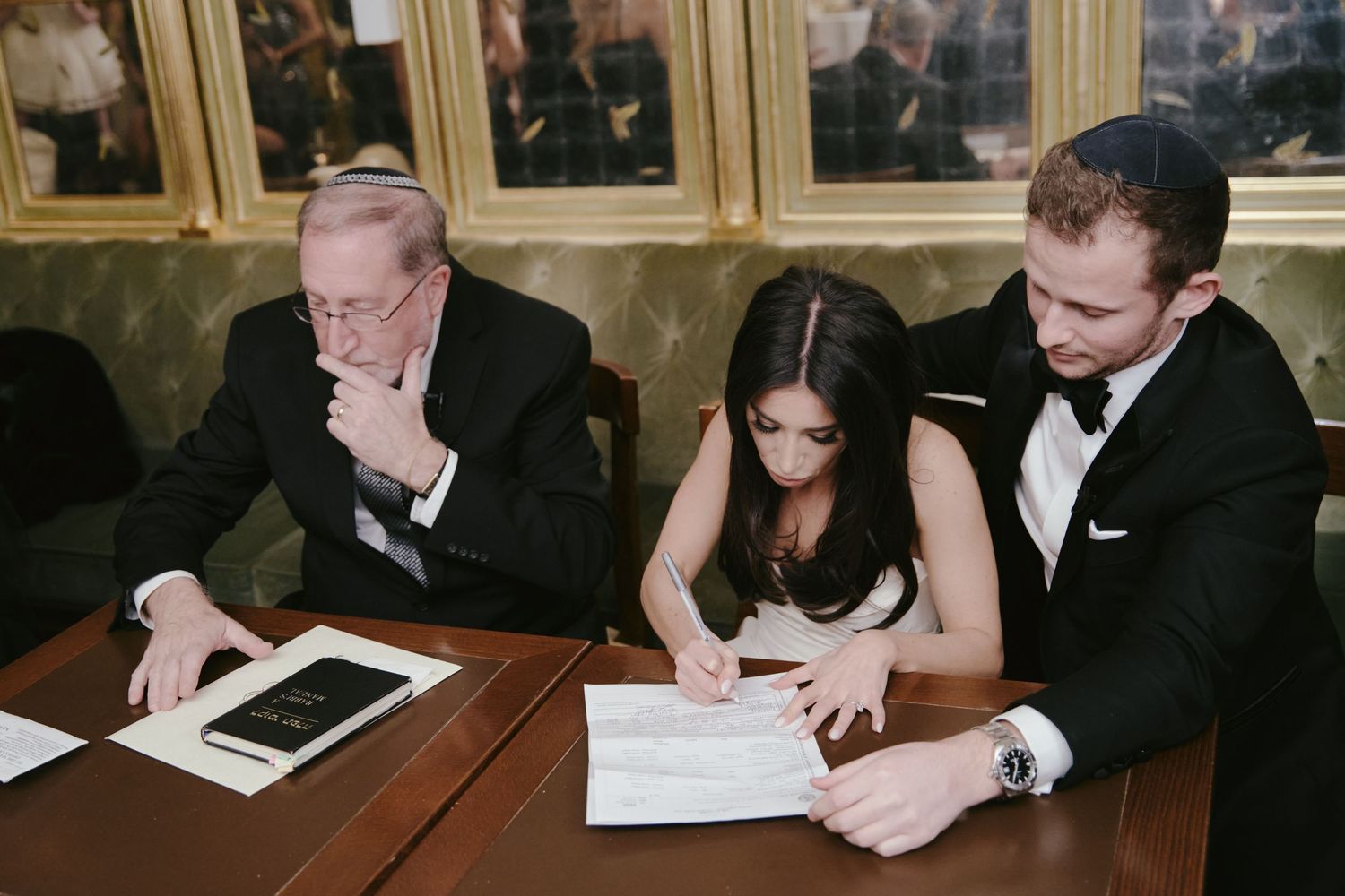 Three people at a table looking through documents and reviewing paperwork together in an elegant setting.