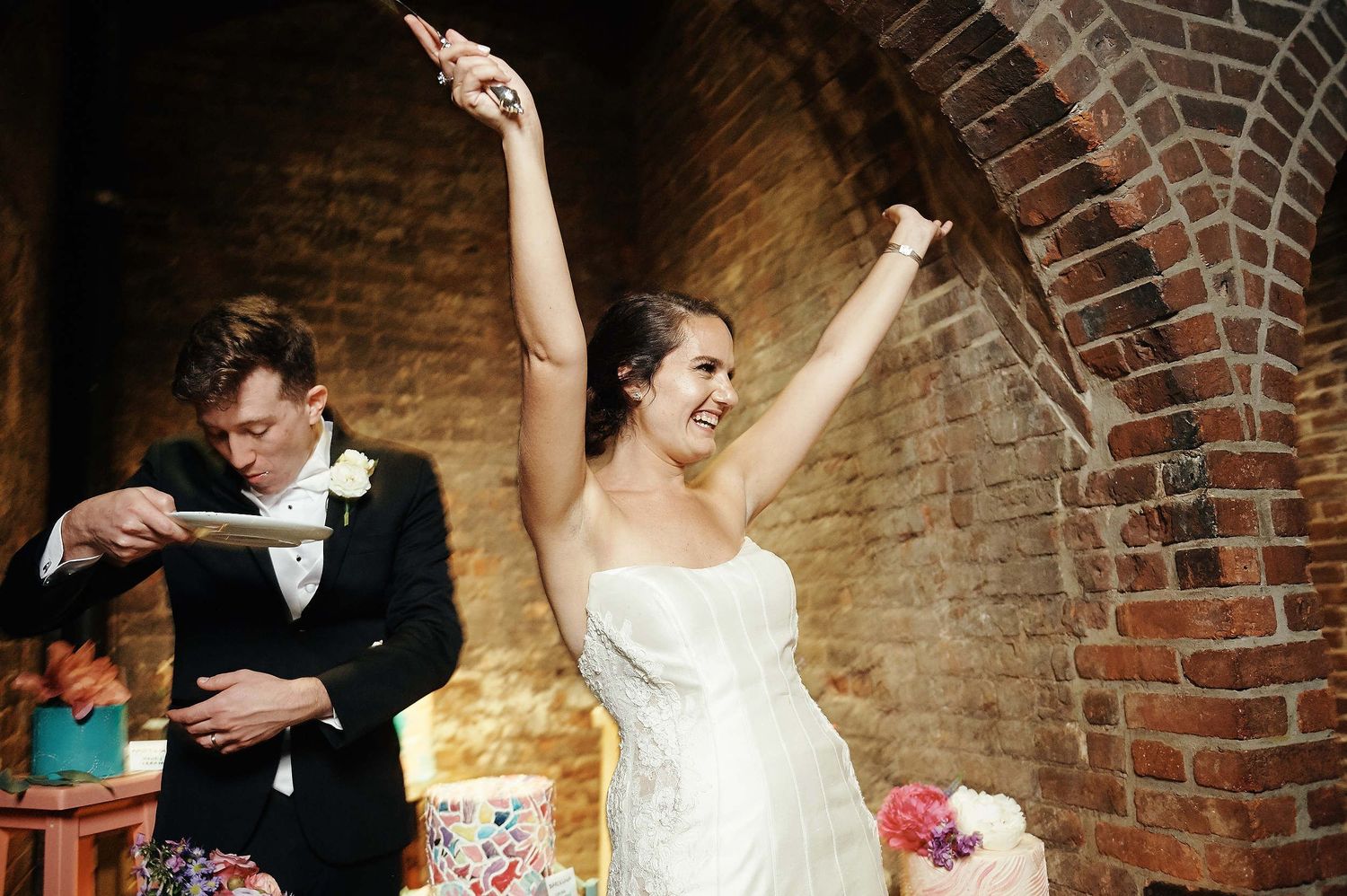 A celebratory moment during a wedding reception in a rustic brick venue.