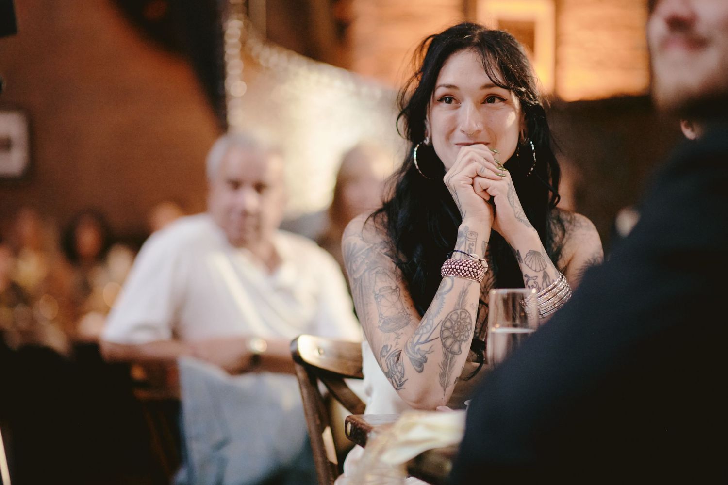 Guest at an evening reception clasps their hands together while listening intently.