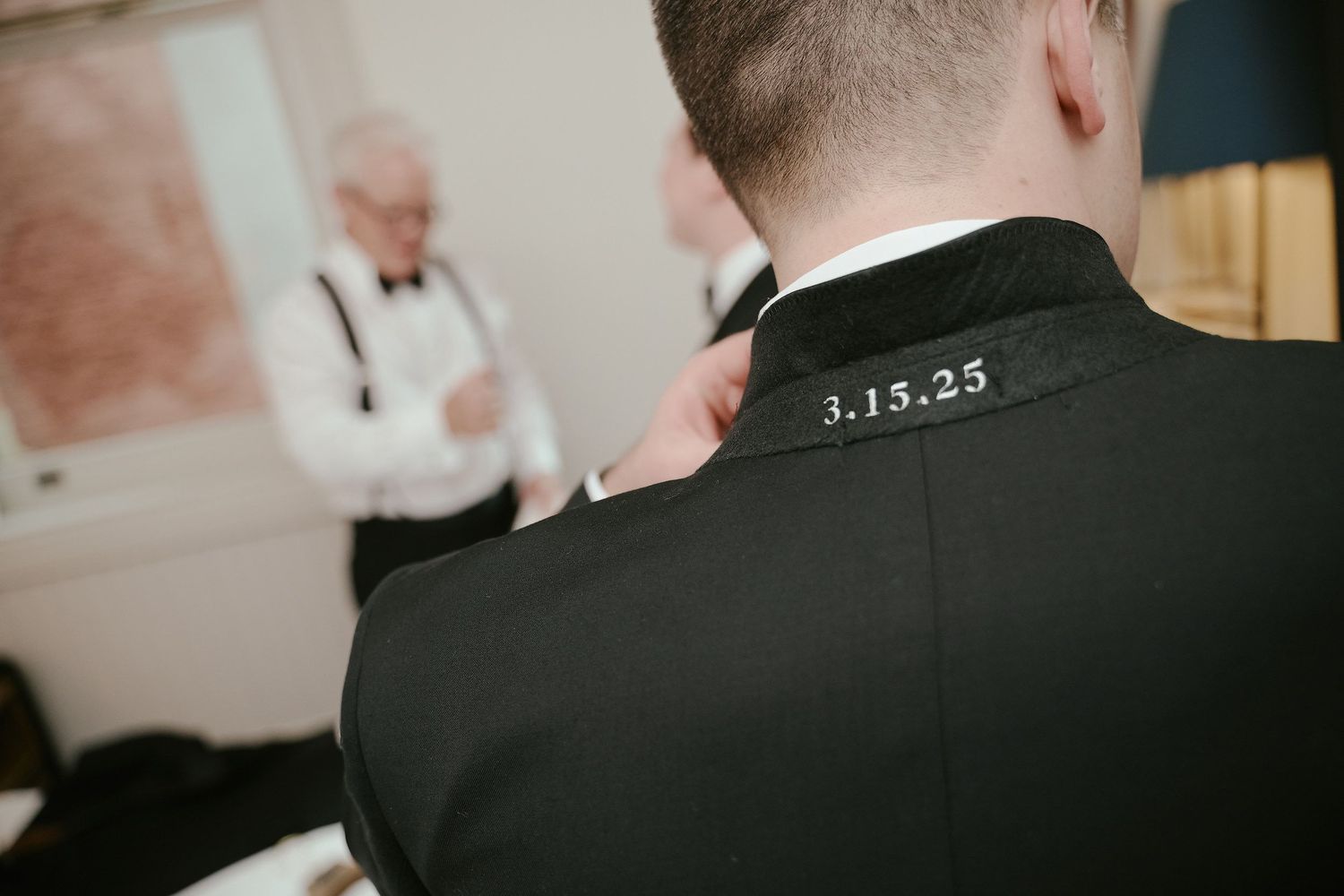 Close-up detail of a groom's suit collar showing an embroidered wedding date.
